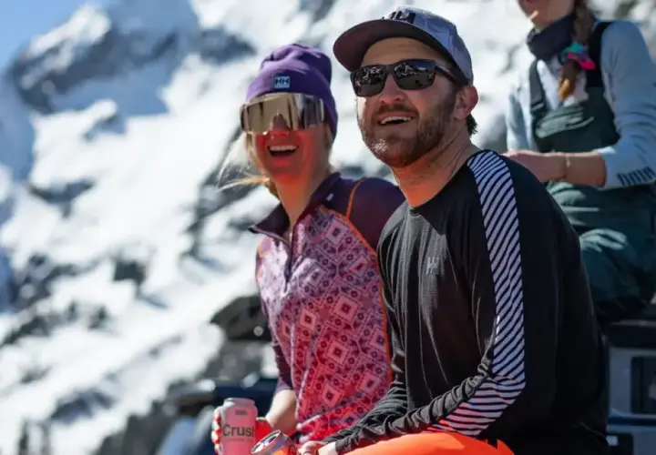 Dos amigos disfrutan del sol en la montaña, abrigados con ropa de poliamida.