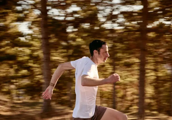 Kilian Jornet corre a toda velocidad en un bosque, capturando la esencia de su último récord.