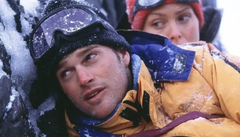Dos escaladores, cubiertos de nieve, luchan contra el frío en una escena de una película de montaña.