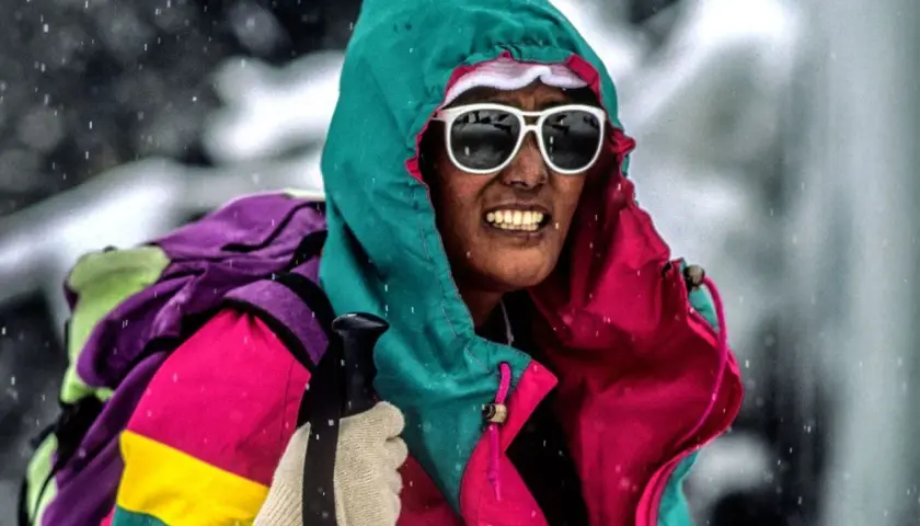 Pasang Lhamu Sherpa, con gafas de sol y gorro, se enfrenta a la nieve con una colorida chaqueta y mochila.