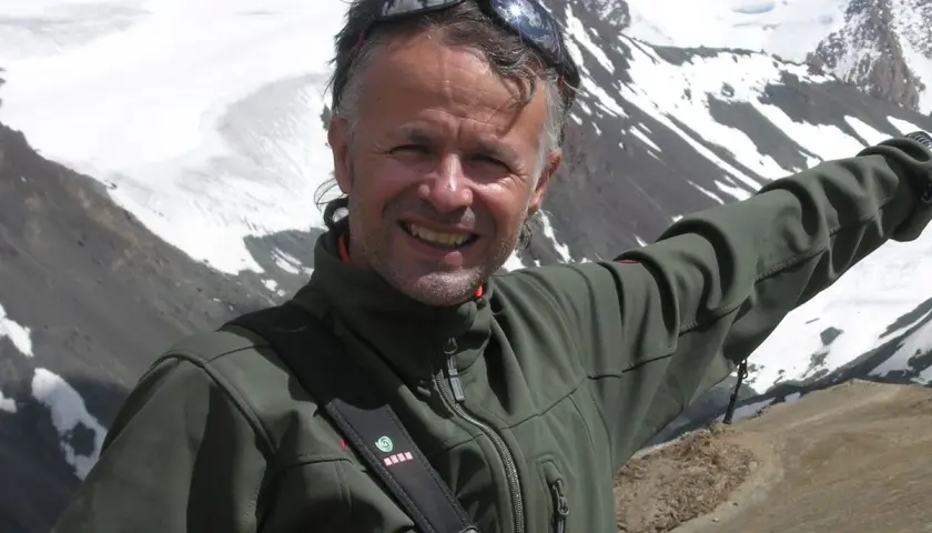 Juanjo Garra, alpinista sonriente, posa con montañas nevadas de fondo.