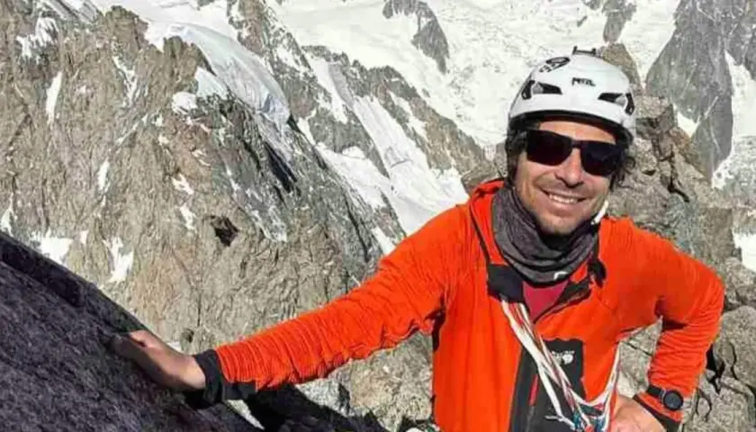 Vivian Bruchez, sonriente y con casco, escala una montaña rocosa y nevada.