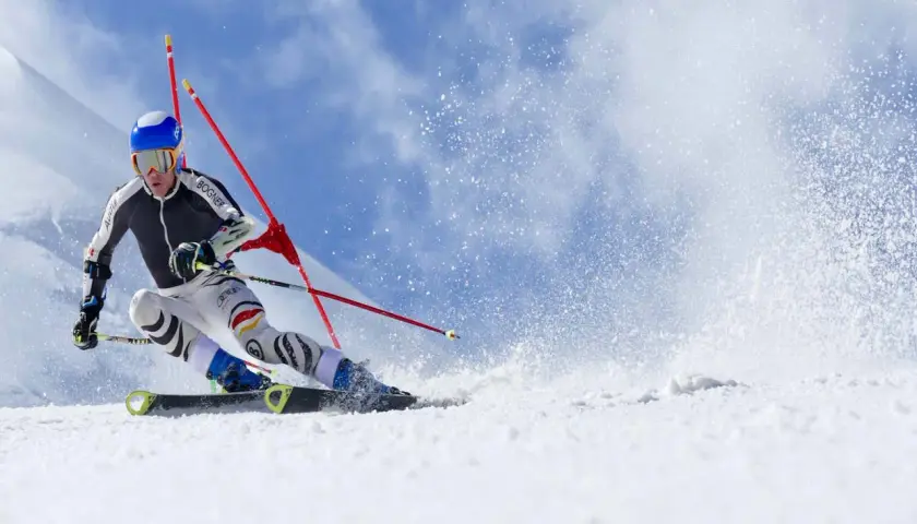 Esquiador compitiendo en slalom, mostrando la diferencia entre esquí alpino y de montaña en una pista nevada.