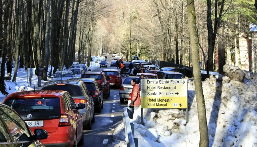 Tráfico en el Montseny con nieve. Coches en fila por la carretera nevada, señalizando la ermita y el hotel.