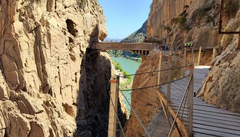 Pasarela de madera sobre un cañón con río verde. Los impresionantes montes bonitos se elevan a ambos lados, creando un paisaje espectacular.