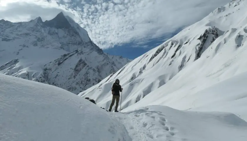 Persona en un sendero nevado, rodeada de imponentes montañas cubiertas de nieve. El senderismo nieve es una aventura inolvidable.