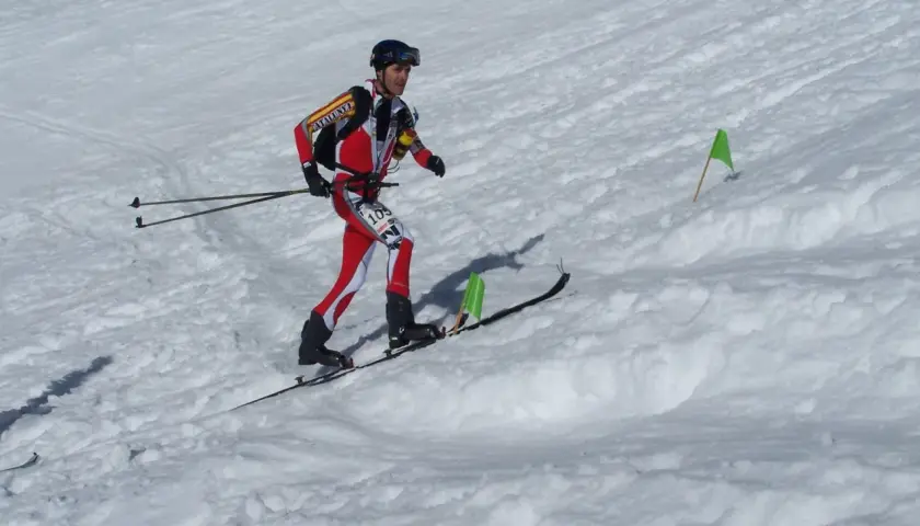 Agustí Roc, esquiador de montaña, compite en una carrera con esquís y bastones, marcado por banderas verdes en la nieve.