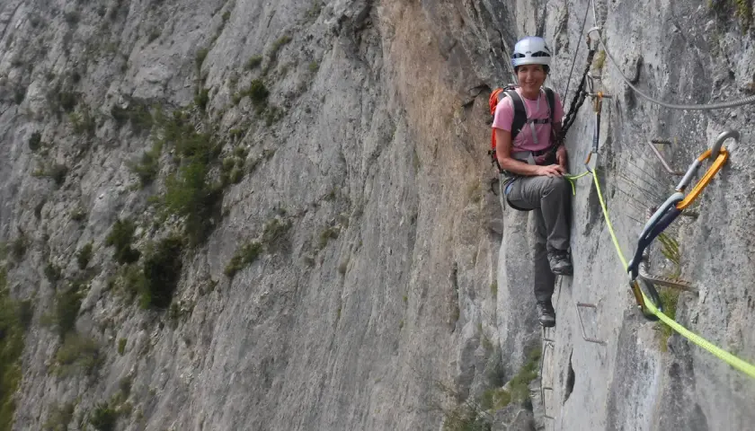 Mujer sonríe en una vía ferrata, disfrutando de la escalada en Benasque.