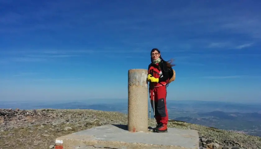 Cumbre del Moncayo, disfrutando de la ruta circular. Una excursionista posa junto al vértice geodésico con bastones de trekking.