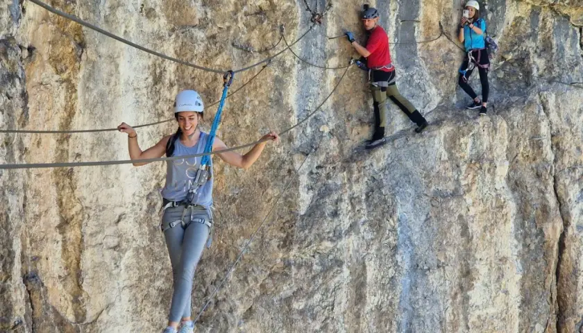 Tres personas disfrutan de una emocionante escalada con cuerda en una pared rocosa.
