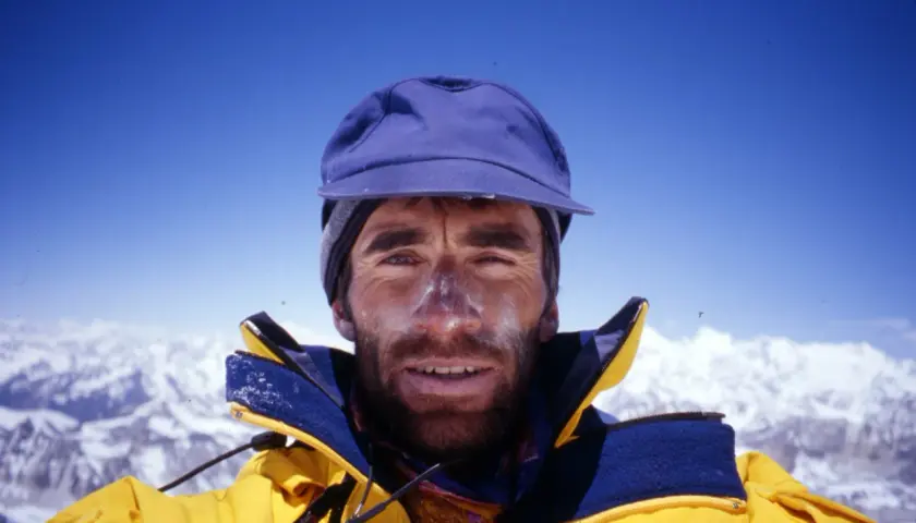 Erhard Loretan, con el rostro marcado por el sol y la nieve, sonríe desde la cima de una montaña.