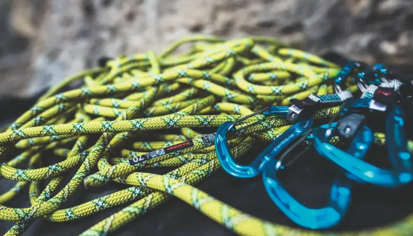 Cuerda de escalada amarilla y verde con mosquetones azules. Lista para lavar y usar en la próxima aventura.