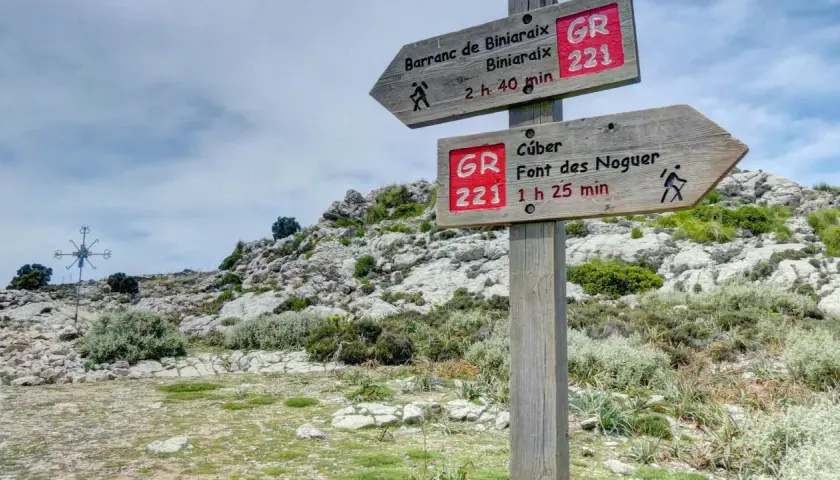 Señalización de ruta GR 221 en un sistema montañoso rocoso. Indica senderos a Barranc de Biniaraix y Cúber.