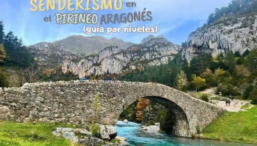 Puente de piedra sobre río turquesa en el Pirineo Aragonés, España. Senderismo entre montañas y bosques otoñales.