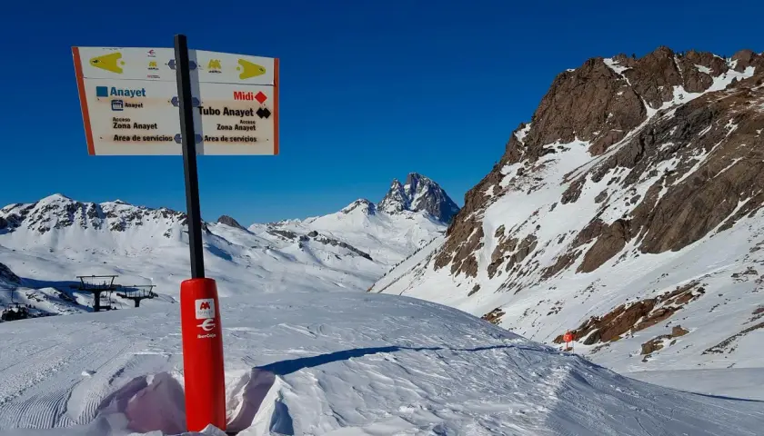 Señalización en la estación de esquí de Formigal, indicando pistas y servicios. Montañas nevadas y cielo azul.