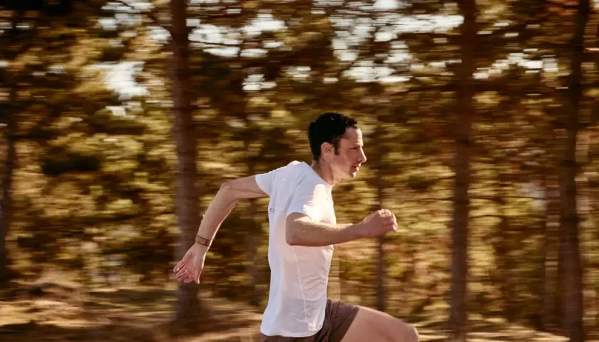 Kilian Jornet corre a toda velocidad en un bosque, capturando la esencia de su último récord.