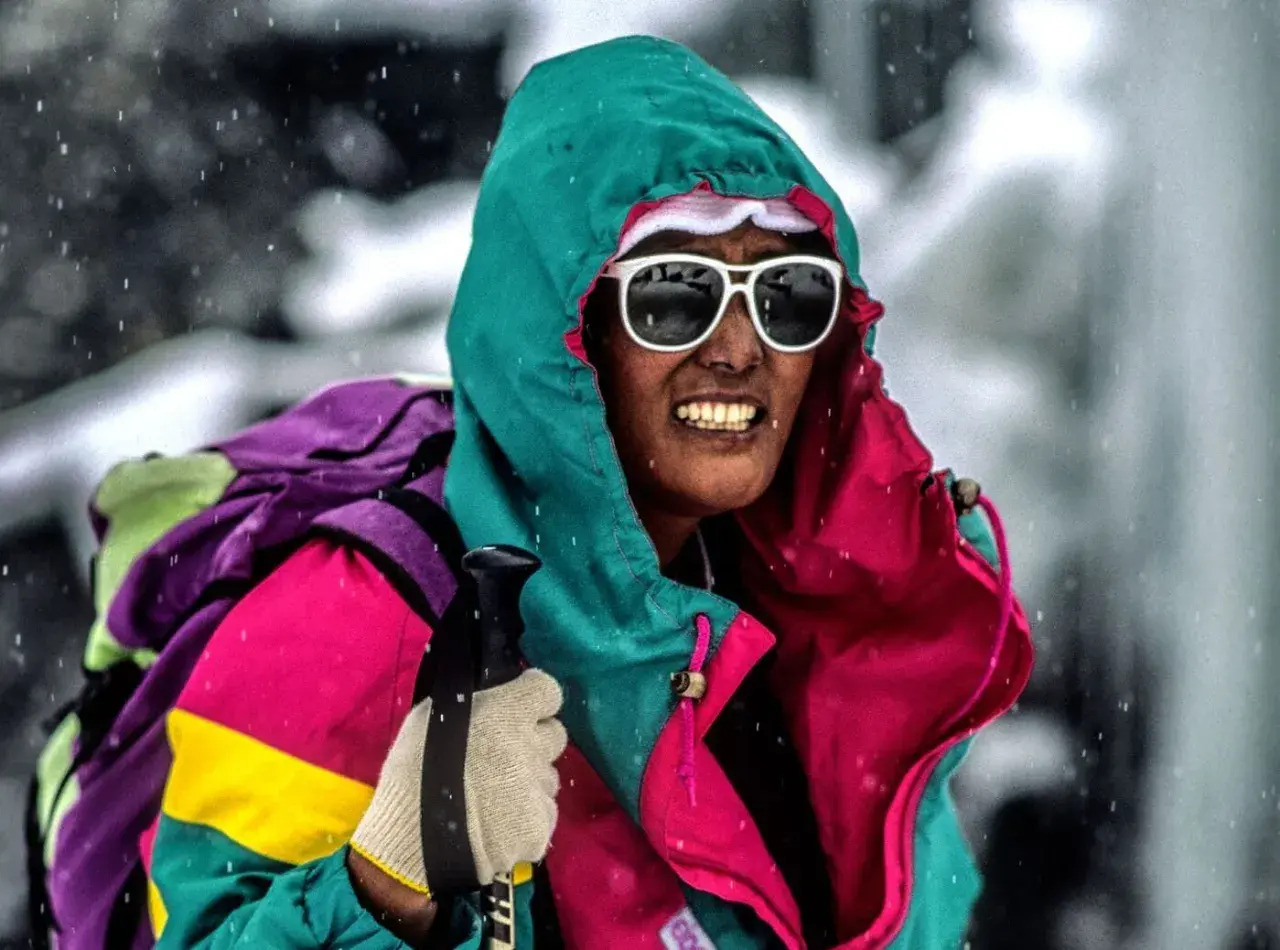 Pasang Lhamu Sherpa, con gafas de sol y gorro, se enfrenta a la nieve con una colorida chaqueta y mochila.