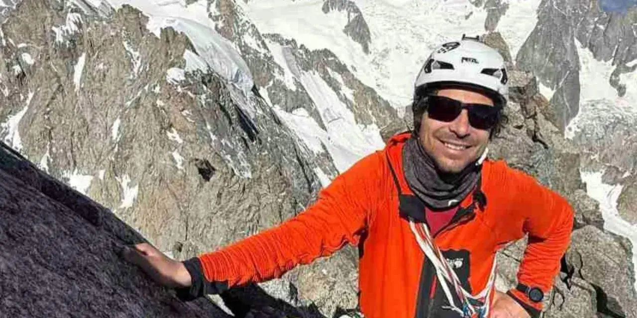 Vivian Bruchez, sonriente y con casco, escala una montaña rocosa y nevada.