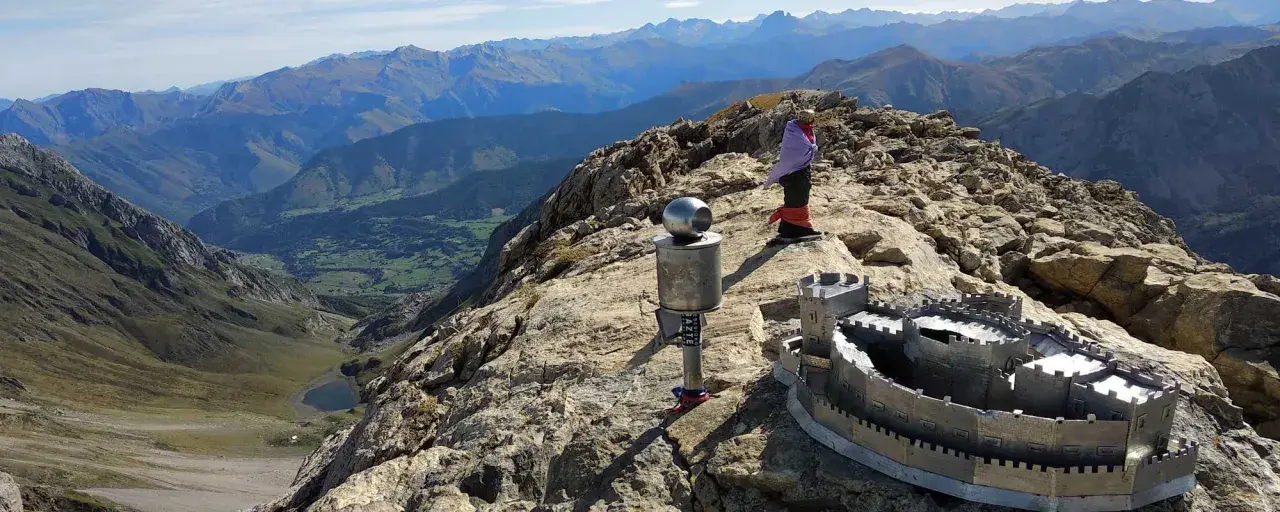 En la cima de una montaña, un monumento con forma de castillo y un poste con una esfera metálica. Al fondo, un valle verde y montañas azules. El **erregeen mahaia** es un lugar de ensueño.