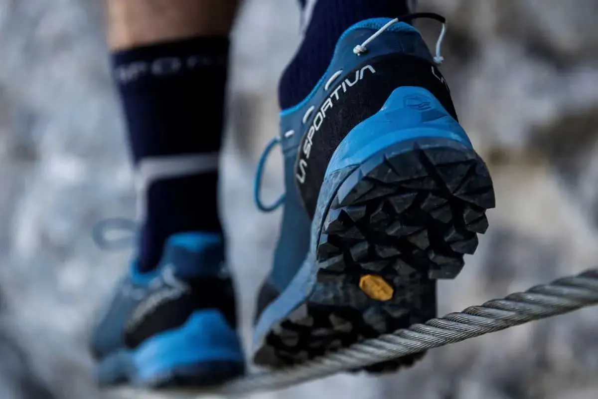 Persona cruza un cable con zapatillas de aproximación La Sportiva, ideales para terrenos difíciles.