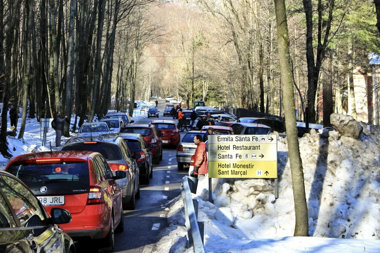 Tráfico en el Montseny con nieve. Coches en fila por la carretera nevada, señalizando la ermita y el hotel.