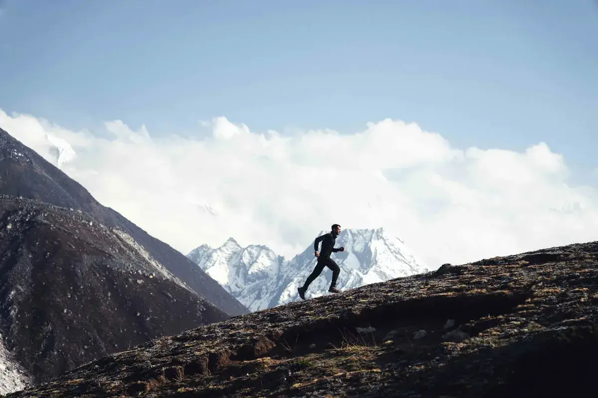 Stephane Brosse corre por una ladera rocosa con picos nevados de fondo.