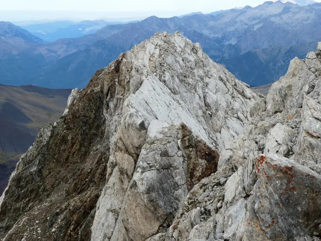 Cresta rocosa y escarpada en el **valle de Vallibierna**, con montañas azules y brumosas al fondo.
