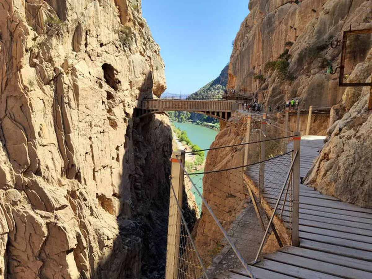 Pasarela de madera sobre un cañón con río verde. Los impresionantes montes bonitos se elevan a ambos lados, creando un paisaje espectacular.