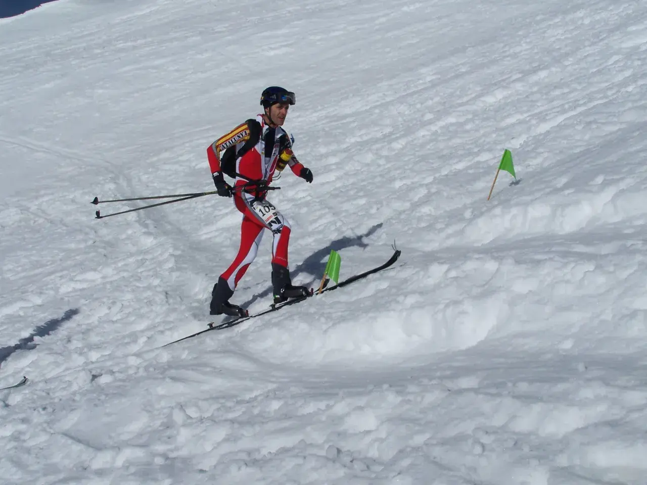 Agustí Roc, esquiador de montaña, compite en una carrera con esquís y bastones, marcado por banderas verdes en la nieve.