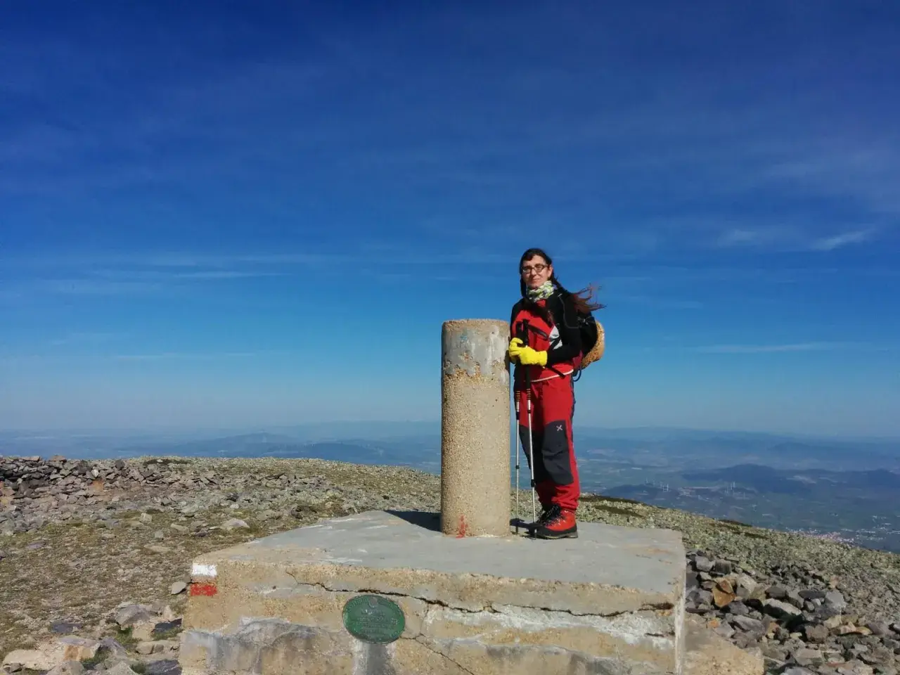 Cumbre del Moncayo, disfrutando de la ruta circular. Una excursionista posa junto al vértice geodésico con bastones de trekking.