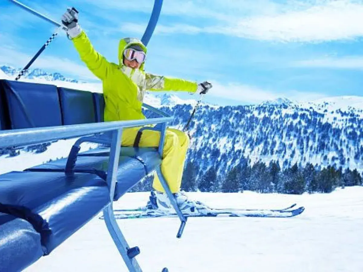 Mujer emocionada en telesilla, lista para hacer sky en la montaña nevada.