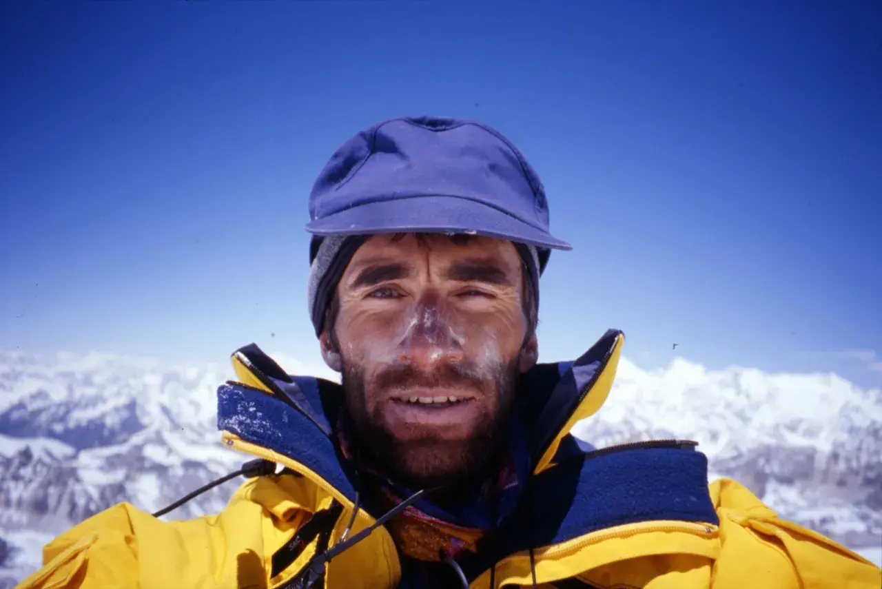 Erhard Loretan, con el rostro marcado por el sol y la nieve, sonríe desde la cima de una montaña.