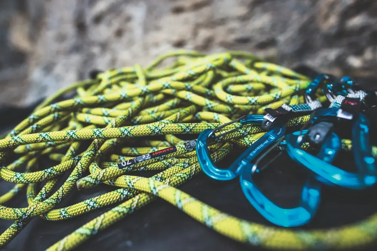 Cuerda de escalada amarilla y verde con mosquetones azules. Lista para lavar y usar en la próxima aventura.