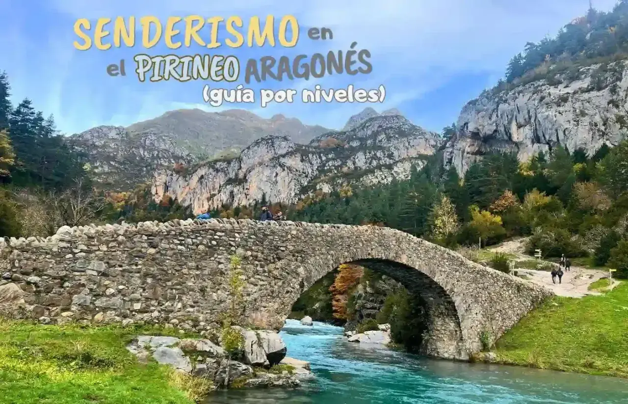 Puente de piedra sobre río turquesa en el Pirineo Aragonés, España. Senderismo entre montañas y bosques otoñales.