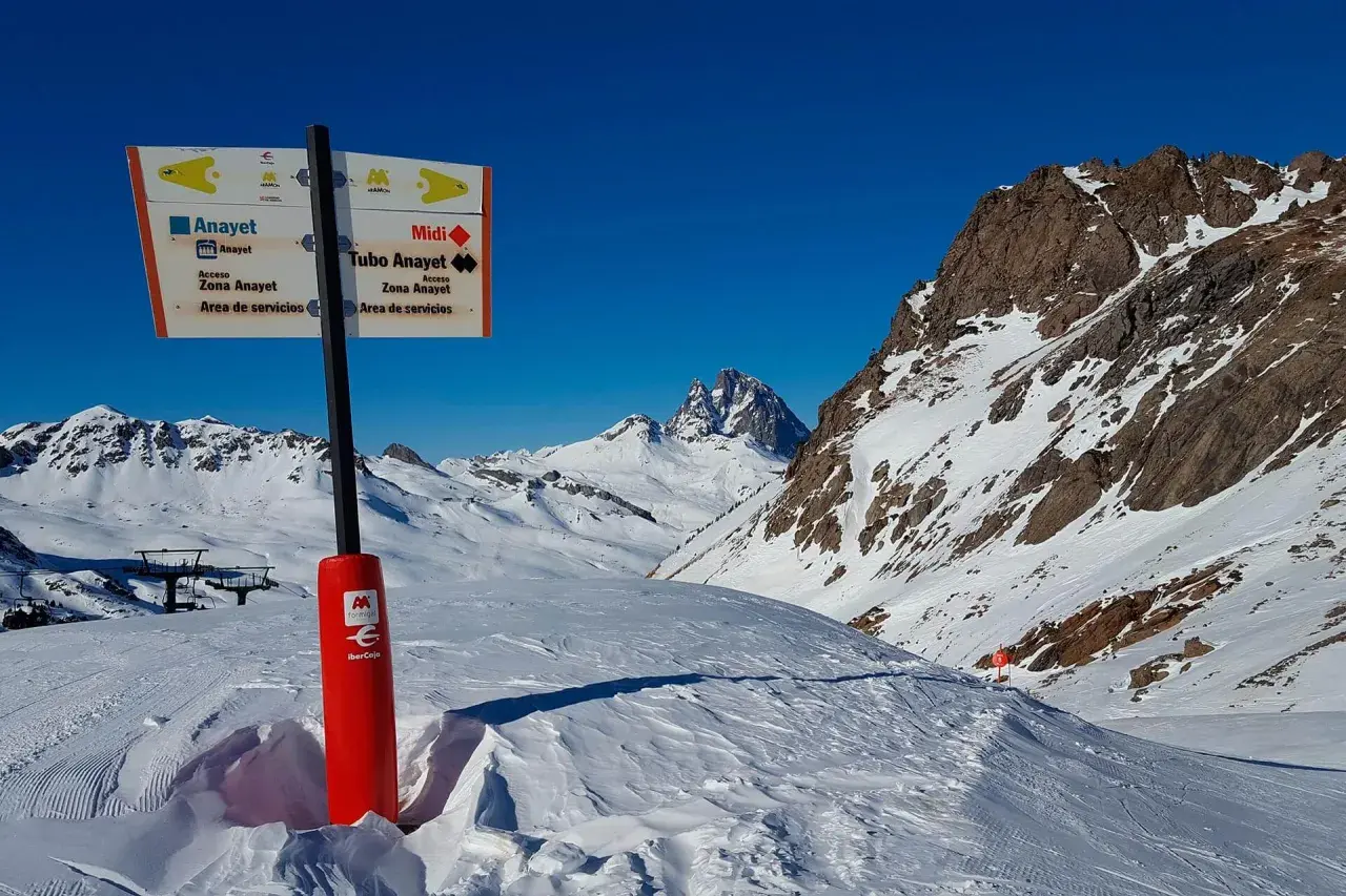 Señalización en la estación de esquí de Formigal, indicando pistas y servicios. Montañas nevadas y cielo azul.
