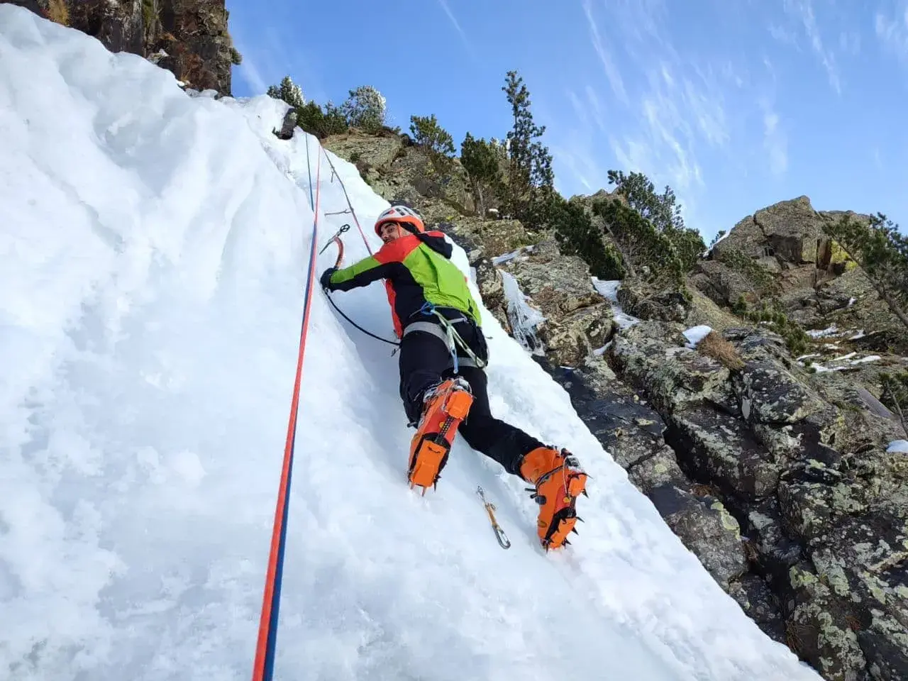 Escalador en hielo en los Pirineos, disfrutando de corredores fáciles con crampones y piolet.