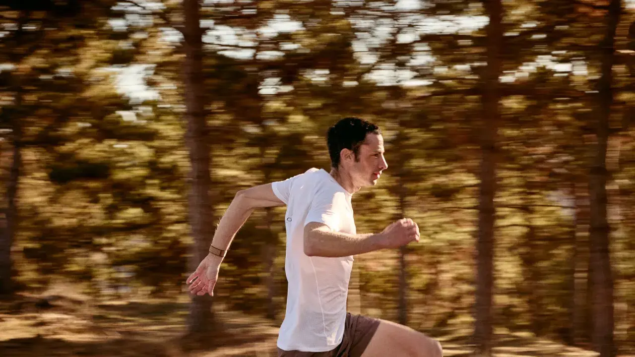 Kilian Jornet corre a toda velocidad en un bosque, capturando la esencia de su último récord.