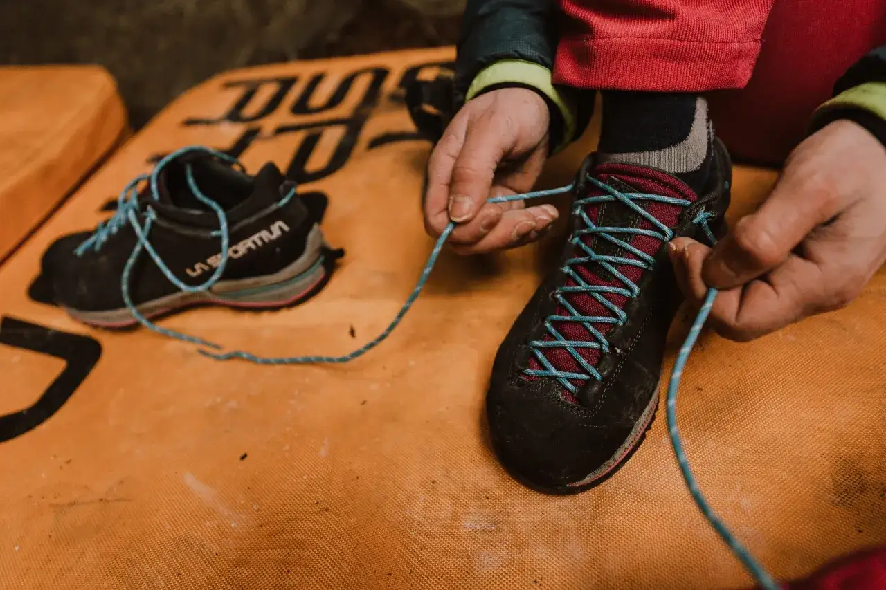 Manos atando cordones de zapatillas de aproximación, listas para la aventura.