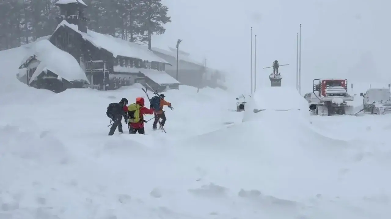 Tres esquiadores avanzan entre la nieve, cerca de un edificio cubierto y veh&iacute;culos sepultados. Las dos avalanchas han transformado el paisaje en un desaf&iacute;o blanco.