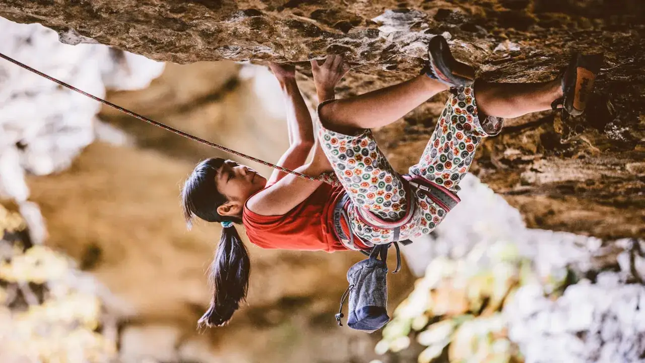 Ashima Shiraishi, escalando una roca con determinación, su cuerpo ágil desafía la gravedad.