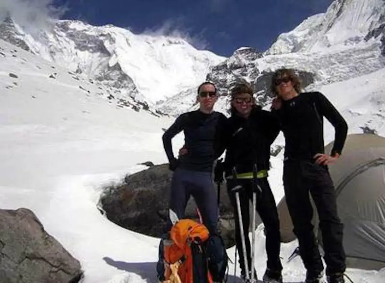 Tres montañistas posan ante un pico nevado. La imagen evoca la expedición donde ocurrió el iñaki ochoa de olza fallecimiento.
