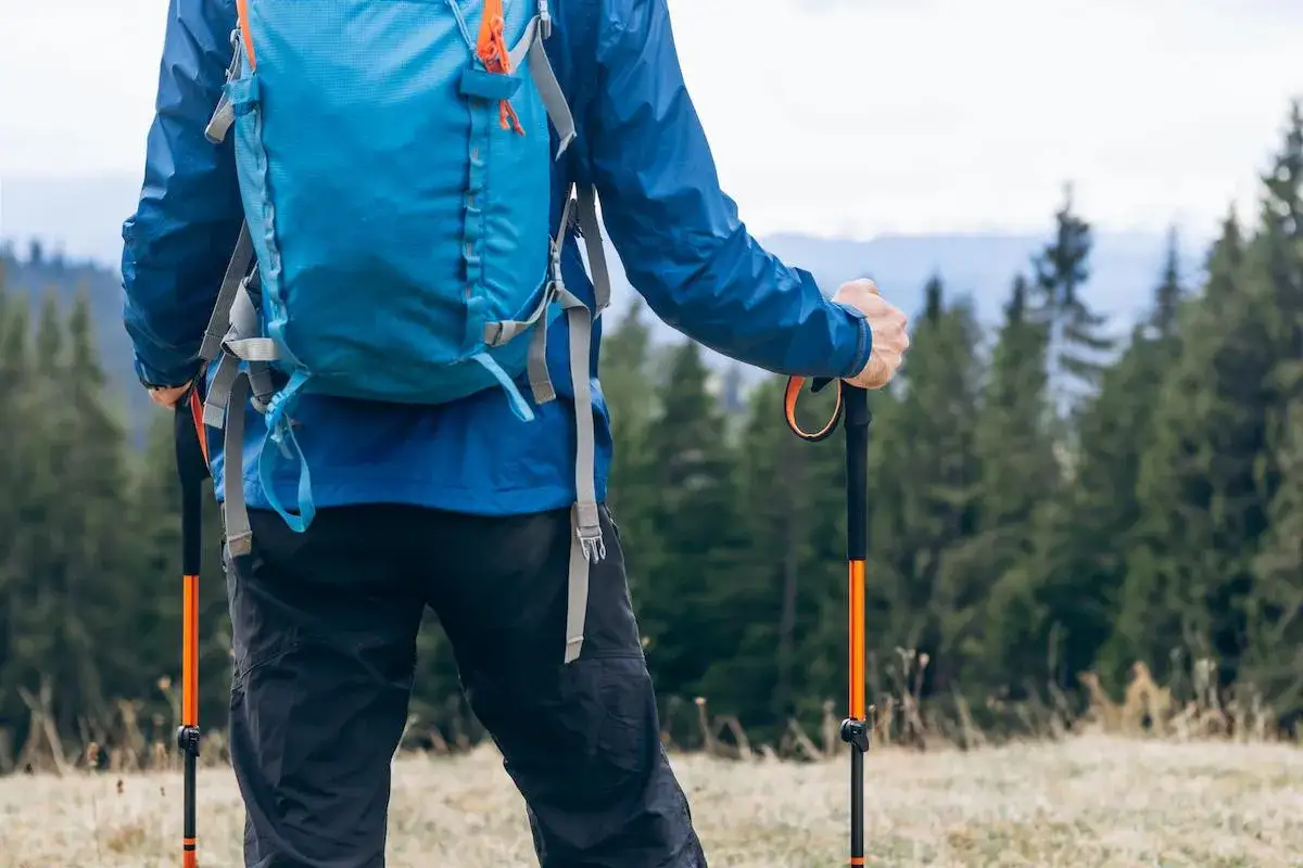 Sender con mochila azul y bastones de trail listos para la aventura.