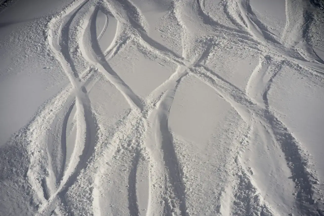 Huellas de esquí en la nieve, mostrando las curvas y los bordes creados por las partes del esquí al deslizarse.