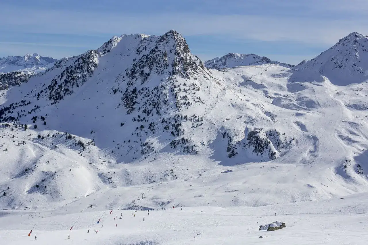 Impresionante paisaje nevado en Formigal, donde la montaña se alza majestuosa. Pistas de esquí y esquiadores disfrutan del día.