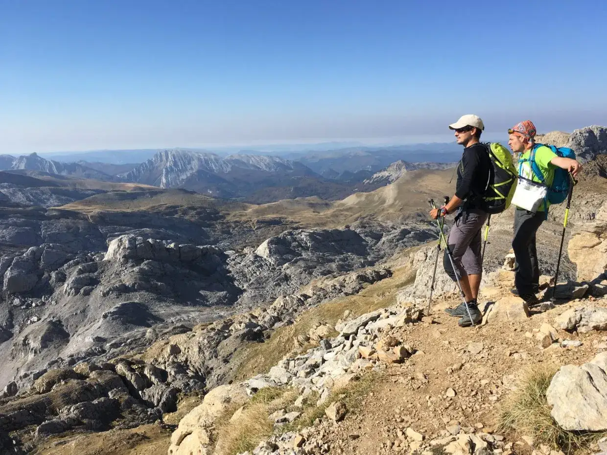 Dos excursionistas contemplan un vasto paisaje montañoso en los Pirineos en España.