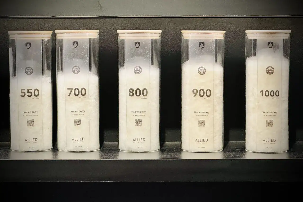 Cinco contenedores transparentes muestran plum&oacute;n de diferentes calidades (550 a 1000), esencial para un plum&iacute;fero.