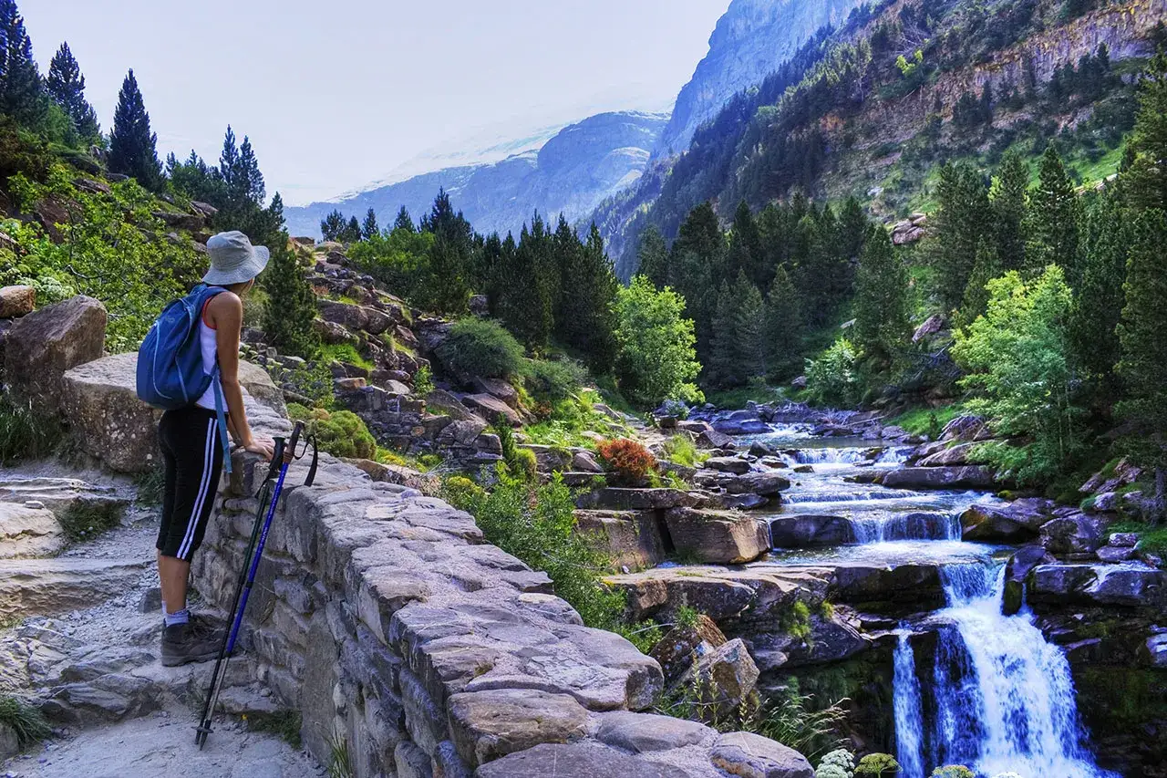 Senderista admira el río y las cascadas en los picos de Huesca.