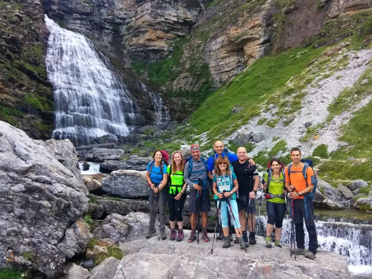 Grupo de senderistas posa frente a una cascada en los Pirineos en España.