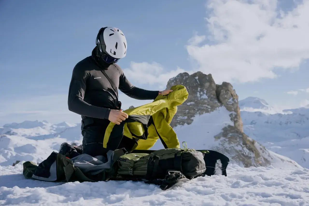 Esquiador se prepara en la monta&ntilde;a, decidiendo entre abrigo Primaloft vs Gore-Tex para el clima.