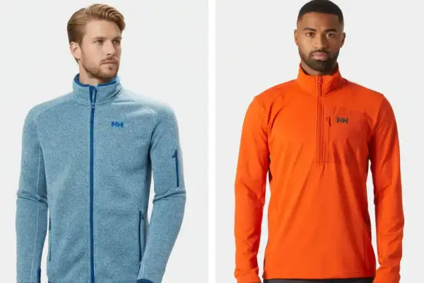 Dos hombres posan con chaquetas Helly Hansen. La de la izquierda es azul jaspeado con cremallera completa, ideal como capa intermedia. La de la derecha es naranja con media cremallera.